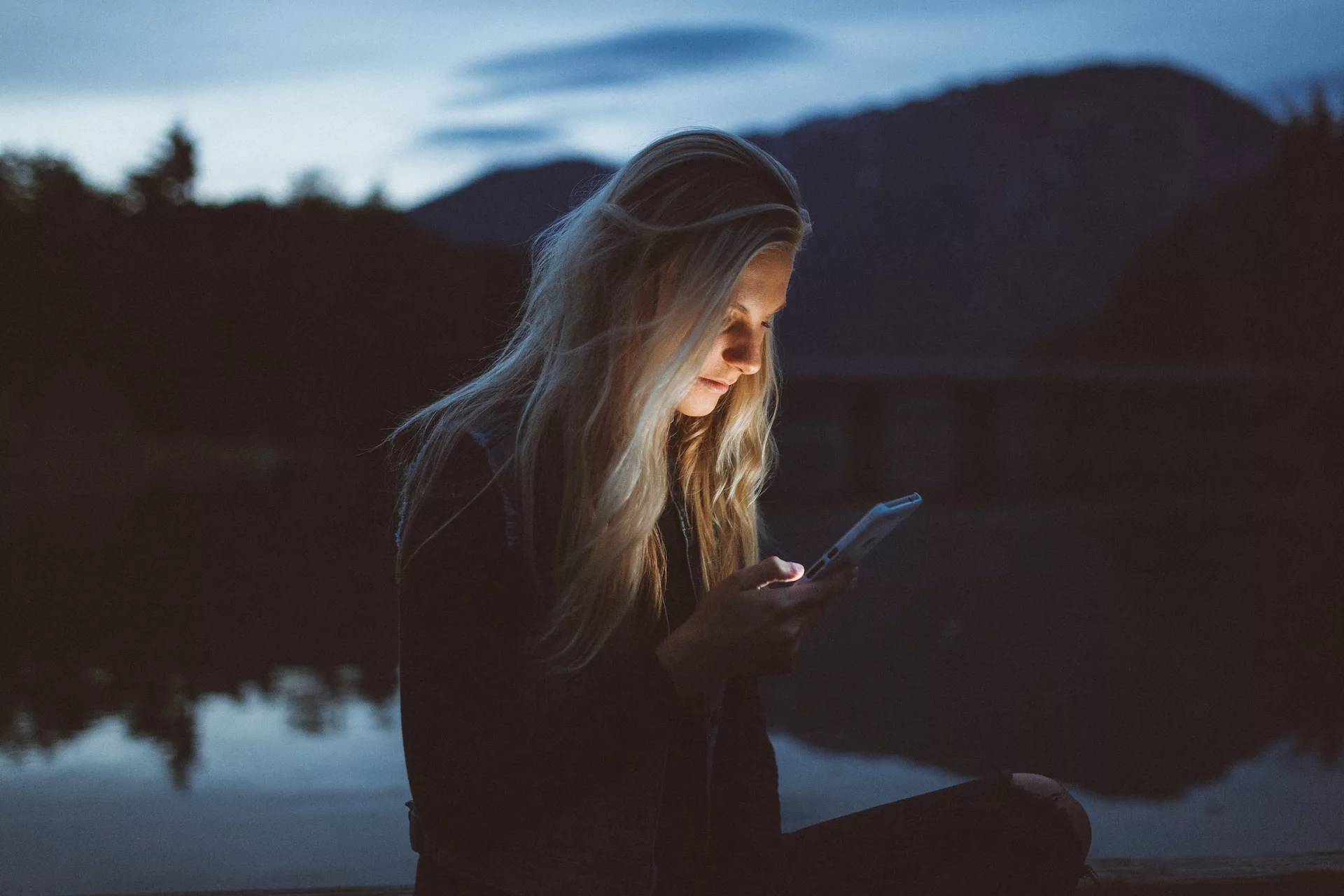 Chica consultando su teléfono en un bosque en la noche
