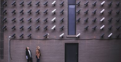 two women facing security camera above mounted on structure