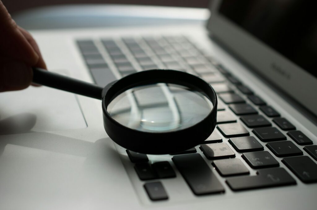 fact checking magnifying glass near gray laptop computer