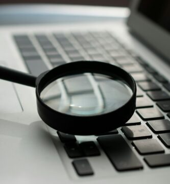 fact checking magnifying glass near gray laptop computer