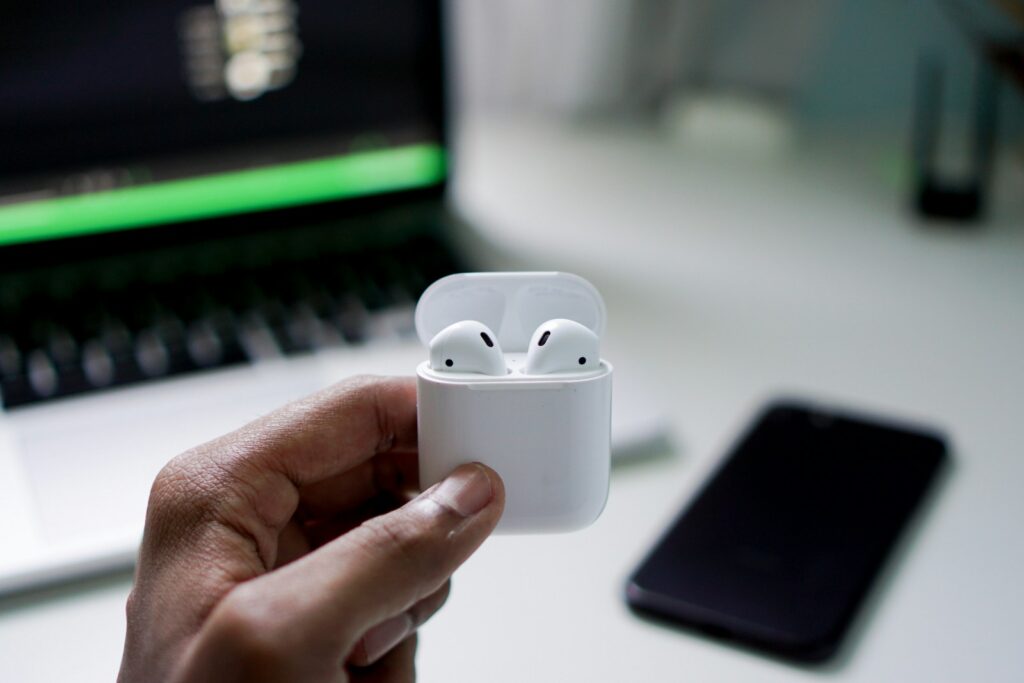 how to connect airpods to laptop person holding wireless earbuds with charging case