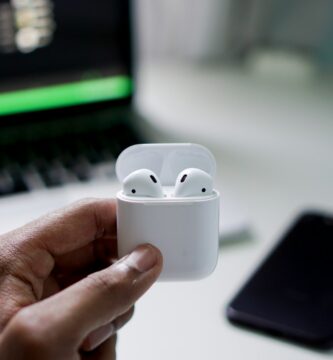 how to connect airpods to laptop person holding wireless earbuds with charging case