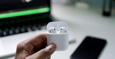 how to connect airpods to laptop person holding wireless earbuds with charging case
