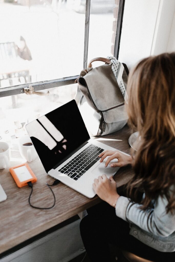 Artículos de Invitado girl wearing grey long-sleeved shirt using MacBook Pro on brown wooden table