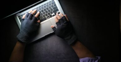Hacking person in black long sleeve shirt using macbook pro