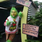 Grinch AI photo prompt a person in a garment holding a sign