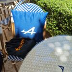 Detalles de marca y aplicaciones del logo azul de Alpine en cojines y mesas