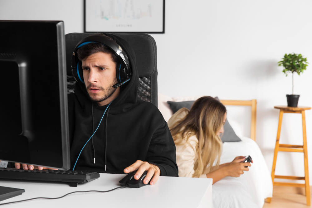 Gamer jugando videojuegos con auriculares en el dormitorio sin hacer ruido.